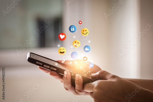 Young man using smartphone sending emojis. Mobile smartphone sending text messages emoji emoticon.