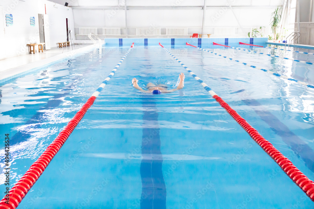 Obraz premium A 70-year-old pensioner is resting, swimming, recovering in the pool with clear and blue water in the hotel.