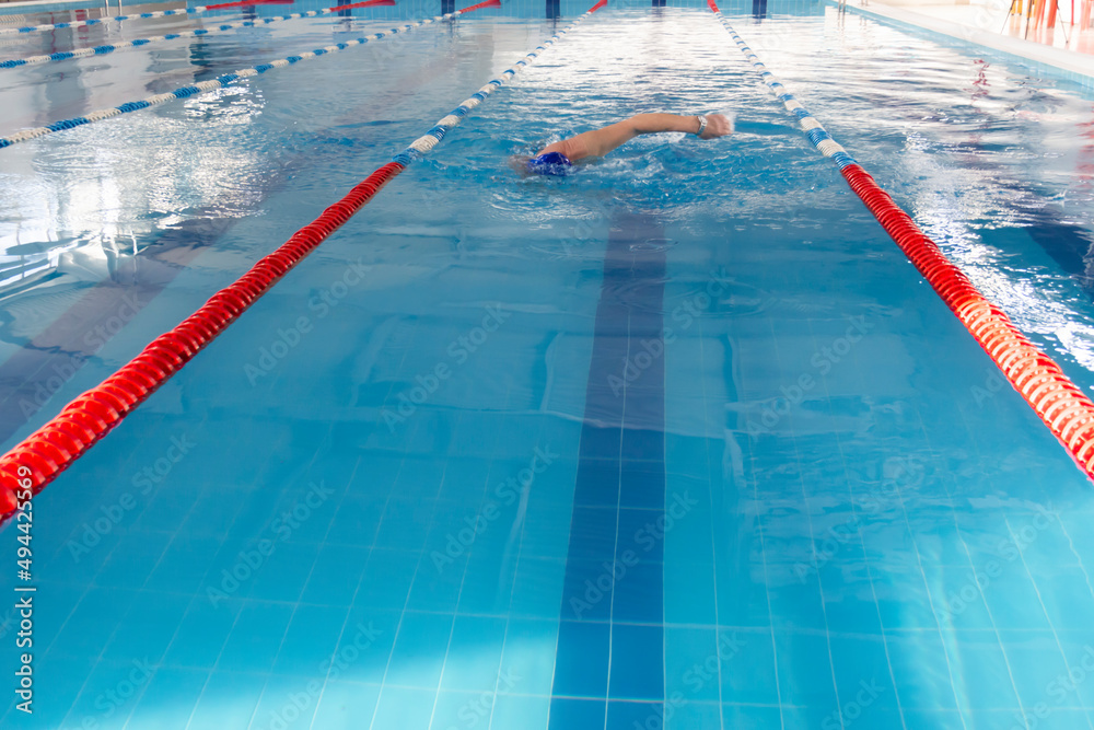 Obraz premium A 70-year-old pensioner is resting, swimming, recovering in the pool with clear and blue water in the hotel.