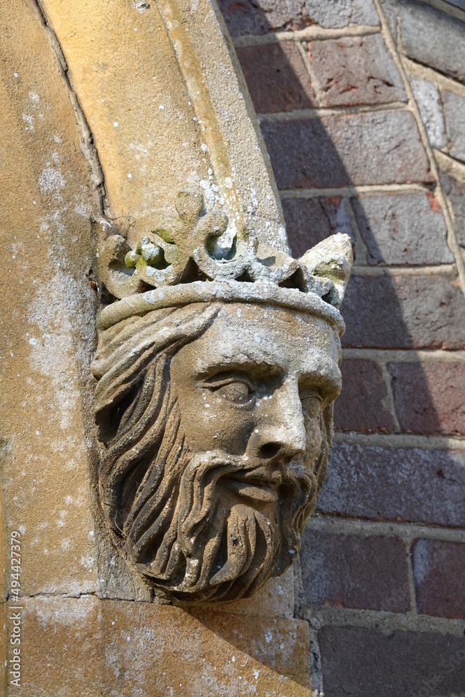 Carved stone head of a bearded king wearing a crown over a church door, Berkshire, England, UK