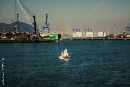 A little old boat in front of a maritime industry