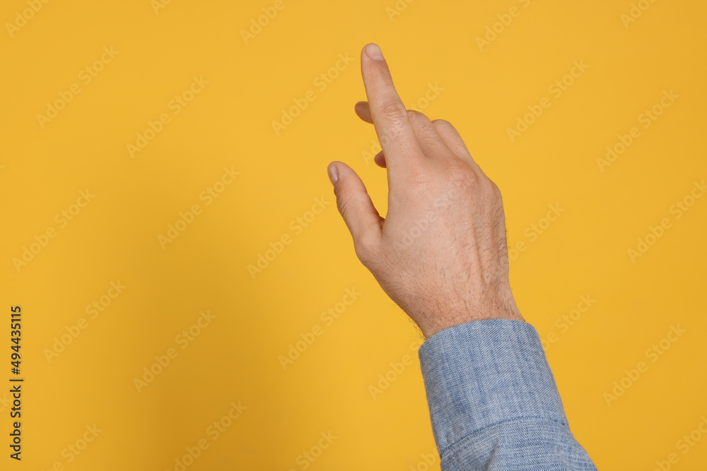 Man pointing at something against yellow background, closeup on hand. Space for text