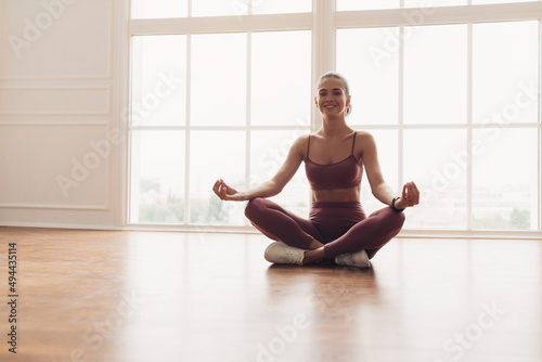 Young woman sitting in lotus position on floor