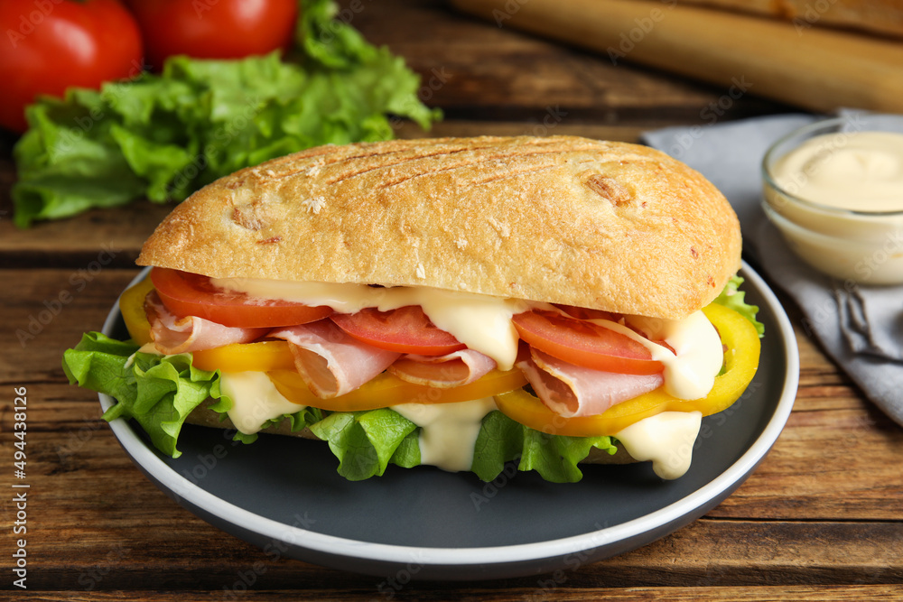Delicious sandwich with vegetables, ham and mayonnaise served on wooden table, closeup Delicious sandwich with vegetables, ham and mayonnaise served on wooden table, closeup