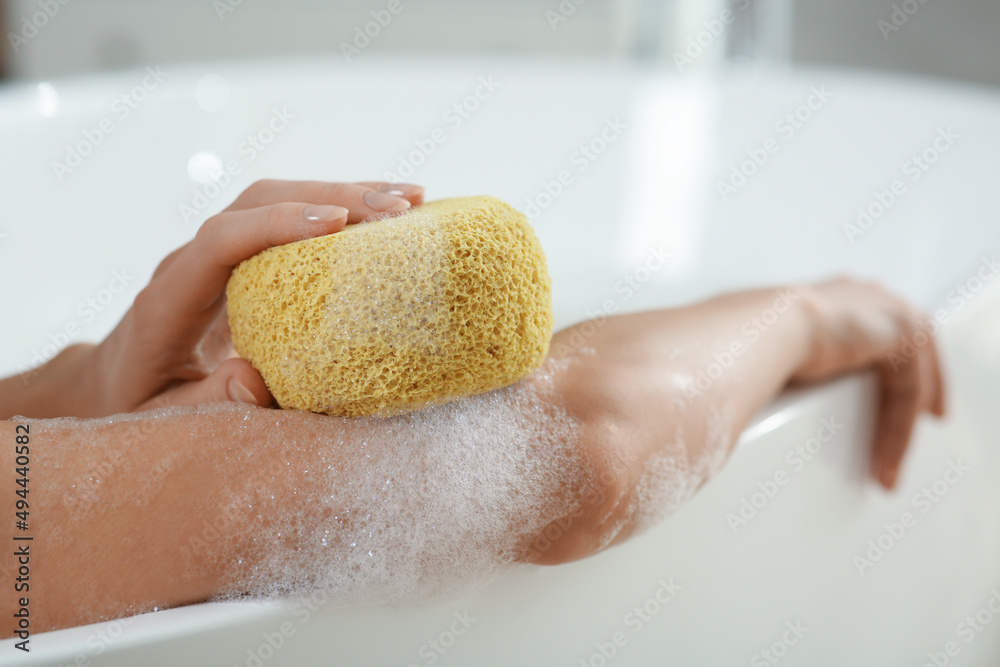 Fototapeta premium Woman with sponge taking bubble bath, closeup
