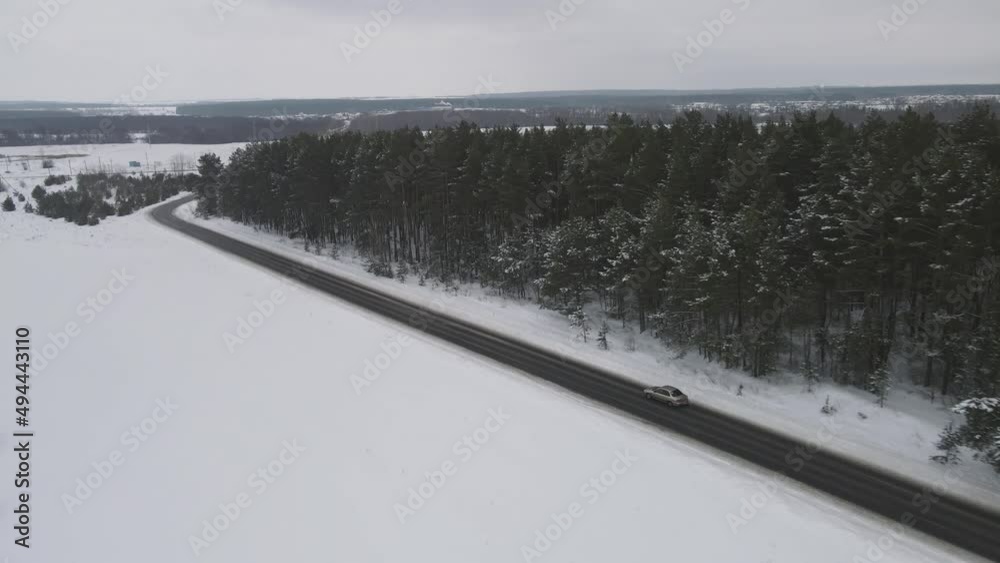 the car moves along the motorway in the winter near the forest. 4k drone footage. the car moves along the motorway in the winter near the forest. 4k drone footage.