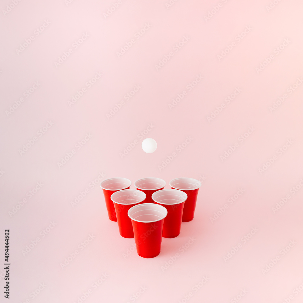 Six red plastic beer pong cups with white ball hovering above. - obrazy, fototapety, plakaty 