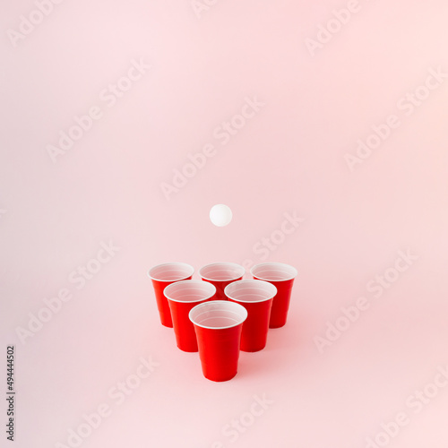 Six red plastic beer pong cups with white ball hovering above.