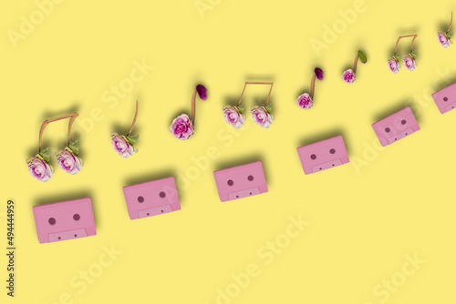 pink retro audio cassettes above them musical notes creatively combined from flowers  creative art music design on a pastel yellow background  copy space