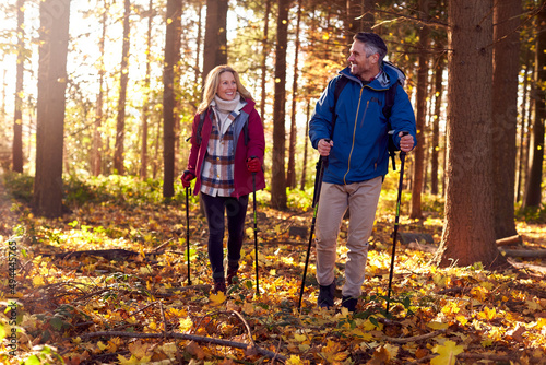 Front View Of Mature Retired Couple Walking Through Fall Or Winter Countryside Using Hiking Poles © Monkey Business