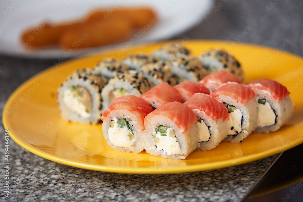 Sushi roll top view on creative orange plate with chopsticks on stone table