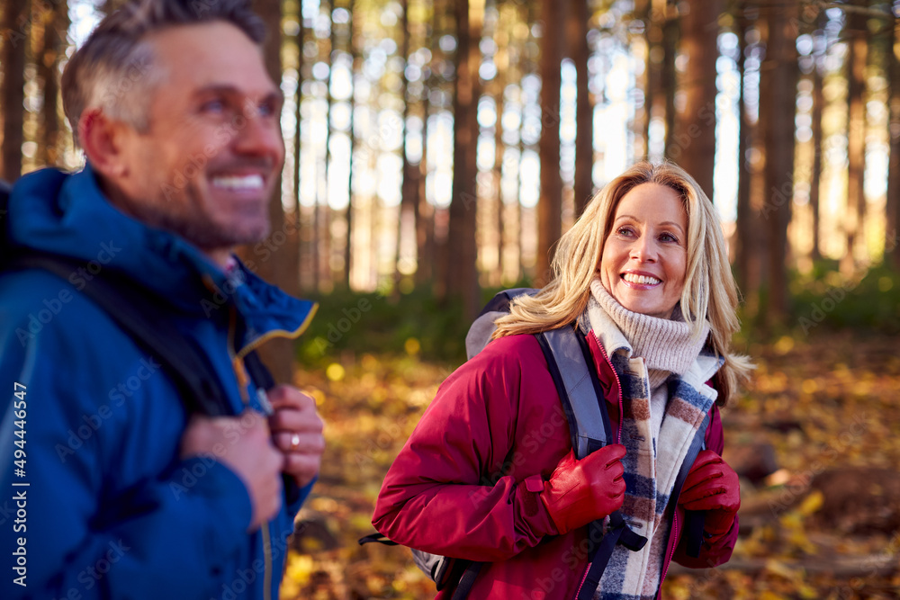 Fototapeta premium Side View Of Mature Retired Couple With Backpacks Walking Through Fall Or Winter Countryside
