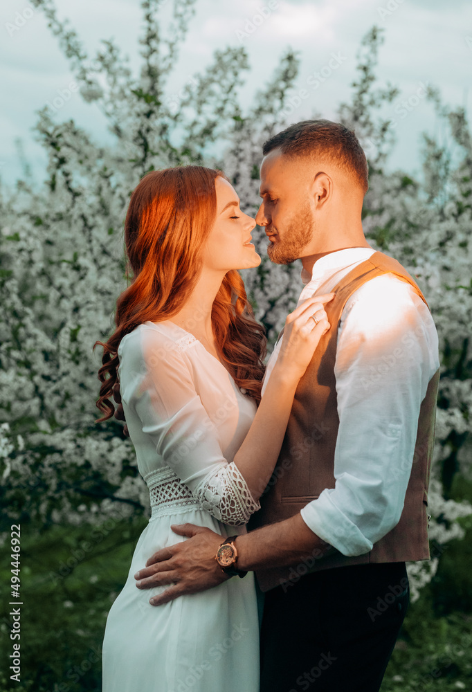 Fototapeta premium Young beautiful wedding couple walking in the night alley of flowering trees.