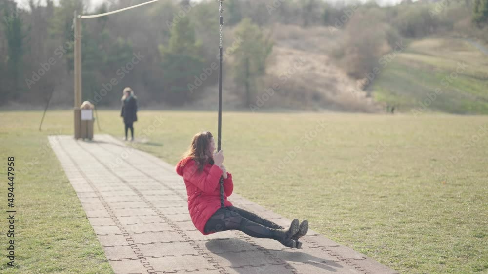 Older woman on kids playground zip line have fun 4K