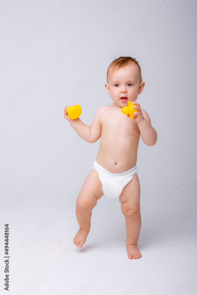 cute baby girl in a diaper playing with a rubber toy duck isolated on a white background cute baby girl in a diaper playing with a rubber toy duck isolated on a white background