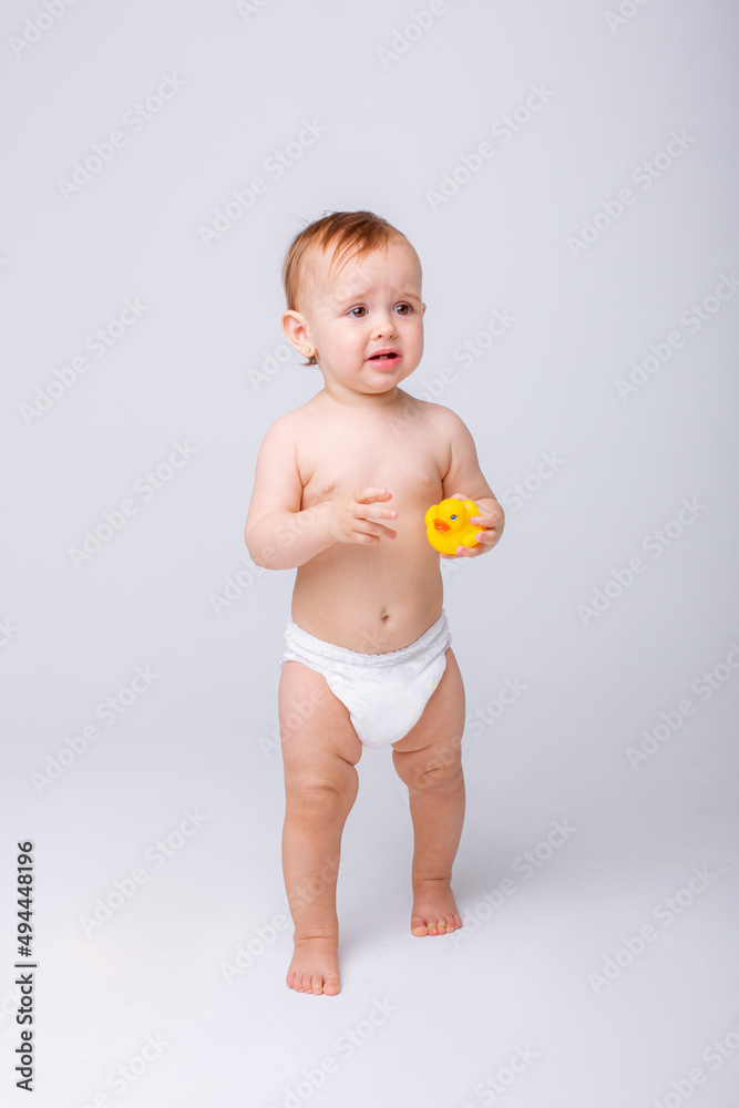 cute baby girl in a diaper playing with a rubber toy duck isolated on a white background cute baby girl in a diaper playing with a rubber toy duck isolated on a white background
