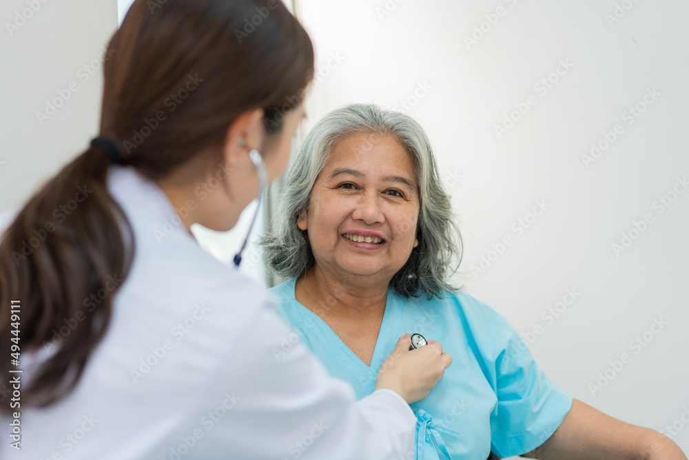 Physician examining heart with a stethoscope and talking with a senior woman at a clinic for check yearly checkup, Medicine health care service and medical insurance concept. Physician examining heart with a stethoscope and talking with a senior woman at a clinic for check yearly checkup, Medicine health care service and medical insurance concept.