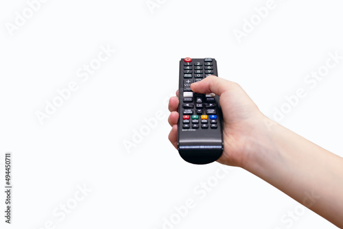 A human hand holds a TV remote control on a white background and presses a button. Control panel with buttons and process control concept. Free space for text and ads photo