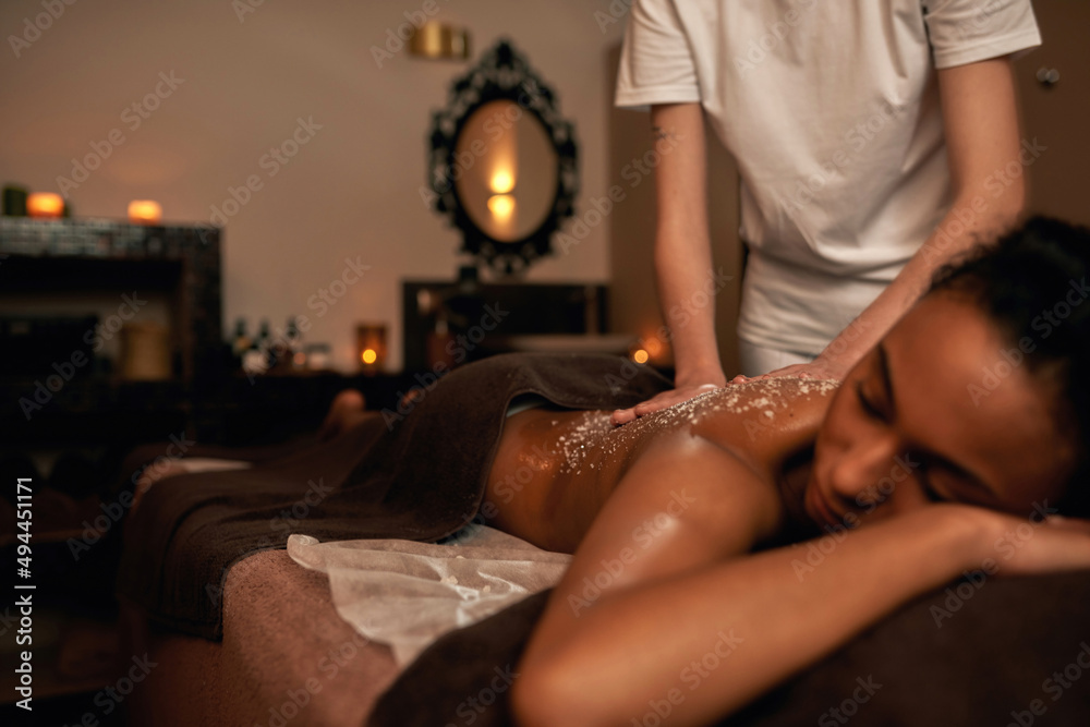 Obraz premium Masseur doing scrub of girl back in spa salon