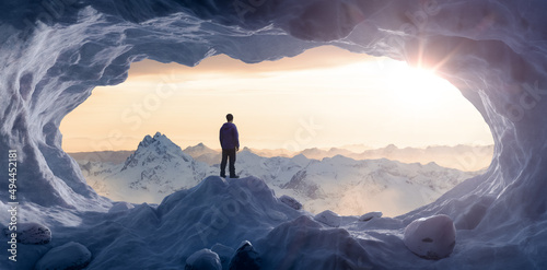 Adventurous Man Hiker standing in an Ice Cave with rocky mountains in background. Adventure Composite. Sunset Sky. 3d Rendering rocks. Aerial Image of landscape from British Columbia, Canada.