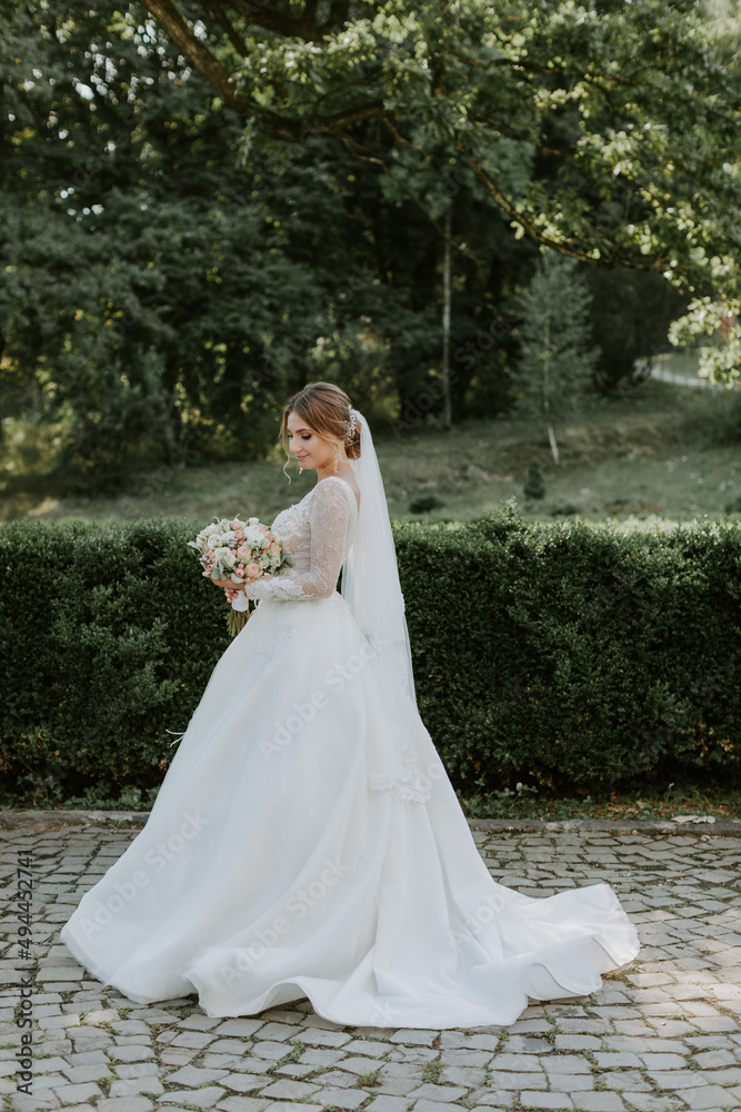 Gorgeous stylish bride in vintage white dress walking in the park