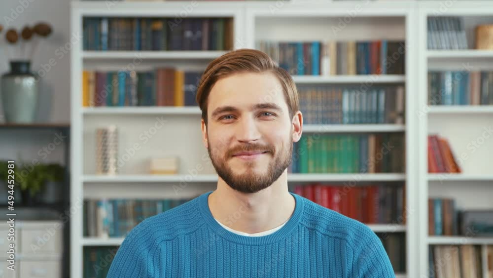 Smiling young man on the background of books in the office, slow motion