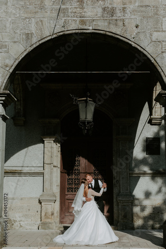 Beautiful magical young bride holding hands handsome groom under castle arc