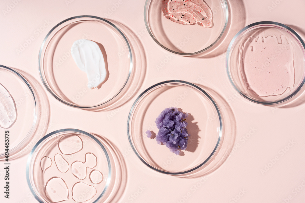 Cosmetic products, scrub, face serum and gel in many petri dishes on a pastel beige background. Cosmetics laboratory research concept. Cosmetic products, scrub, face serum and gel in many petri dishes on a pastel beige background. Cosmetics laboratory research concept.