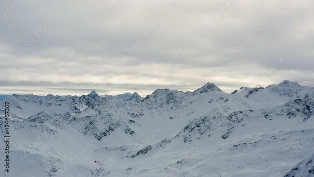 Aerial trucking shot of the majestic alpine peaks in the famous Swiss ski resort Arosa covered in snow on cloudy weather Aerial trucking shot of the majestic alpine peaks in the famous Swiss ski resort Arosa covered in snow on cloudy weather