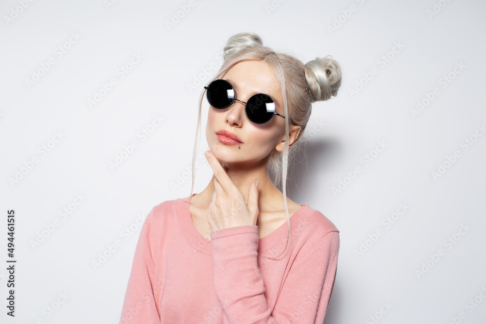 Studio portrait of beautiful blonde girl with two hair buns wearing sunglasses. Studio portrait of beautiful blonde girl with two hair buns wearing sunglasses.
