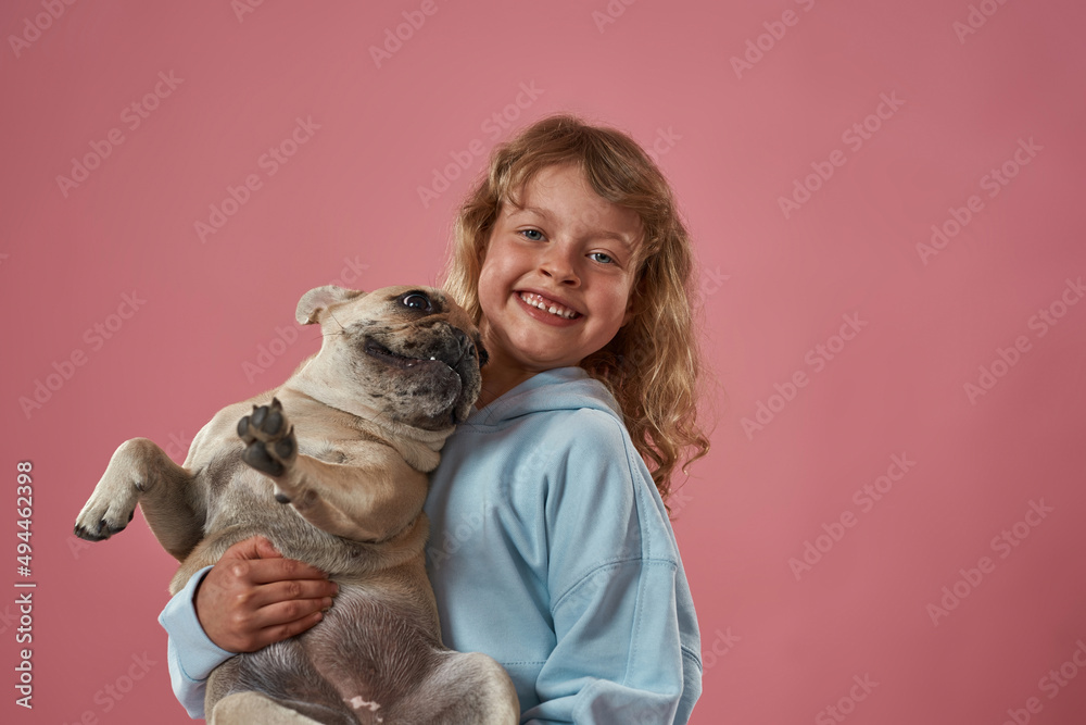 Obraz premium Happy caucasian little girl holding French bulldog