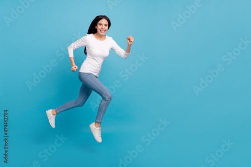 Full length body size view of attractive cheerful purposeful girl jumping running isolated on bright blue color background
