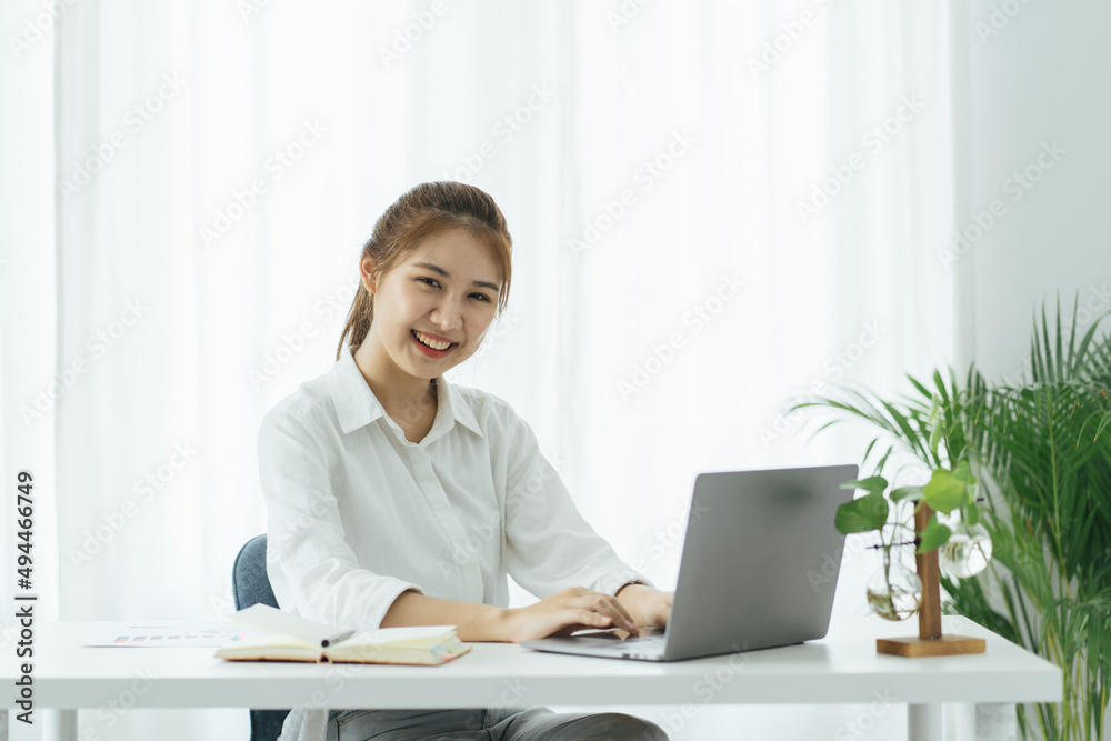 Charming asian businesswoman sitting working on laptop in office. Charming asian businesswoman sitting working on laptop in office.