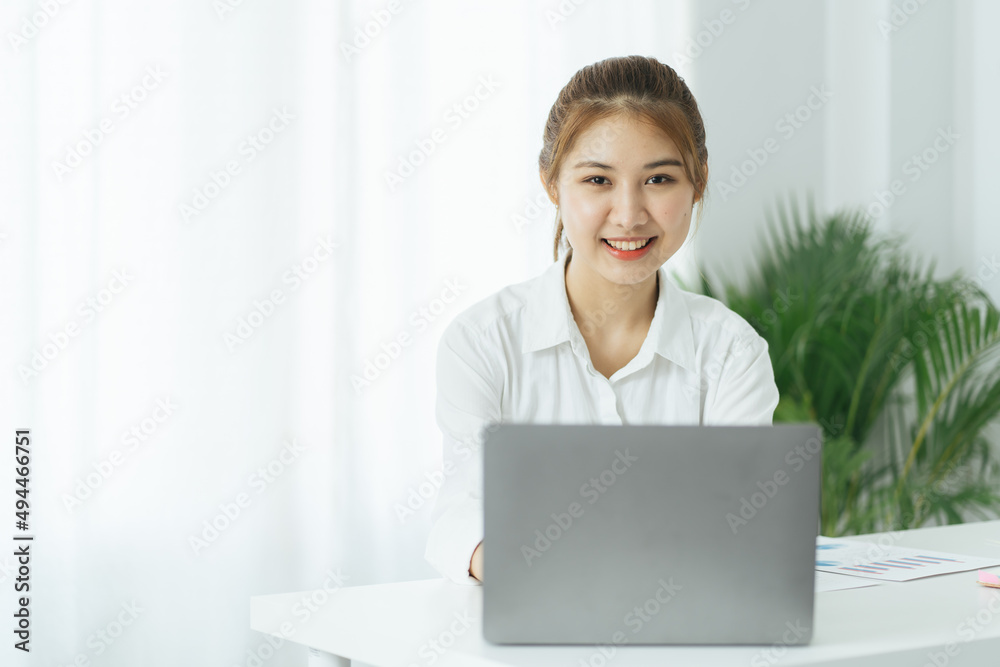 Happy young asian businesswoman sitting on her workplace in the office. Young woman working at laptop in the office. Happy young asian businesswoman sitting on her workplace in the office. Young woman working at laptop in the office.