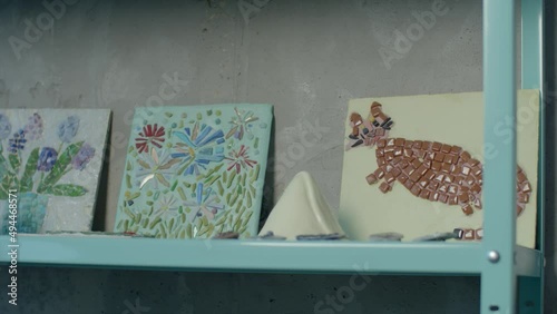 Children's creativity: paintings in the technique of stone mosaics, ceramic and clay products. Close-up, daylight Crafts are on the shelf, continued work photo