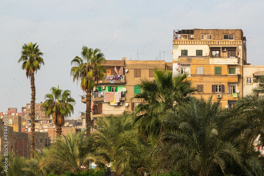 Cairo, Egypt - January 2022: Typical house with linen on the balcony and some palm trees in the city centre