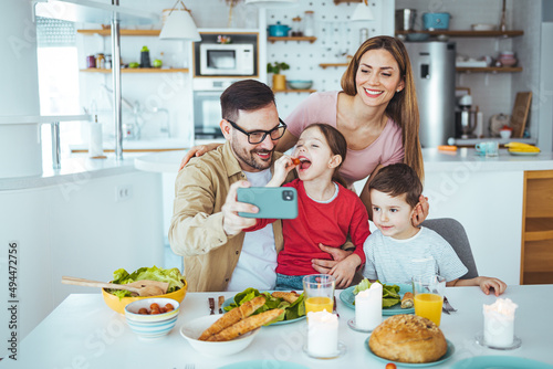 Smiling father holding cellphone  making selfie shot  recording video with happy wife and little kids siblings. Excited parents looking at mobile screen with kids  feeling excited.