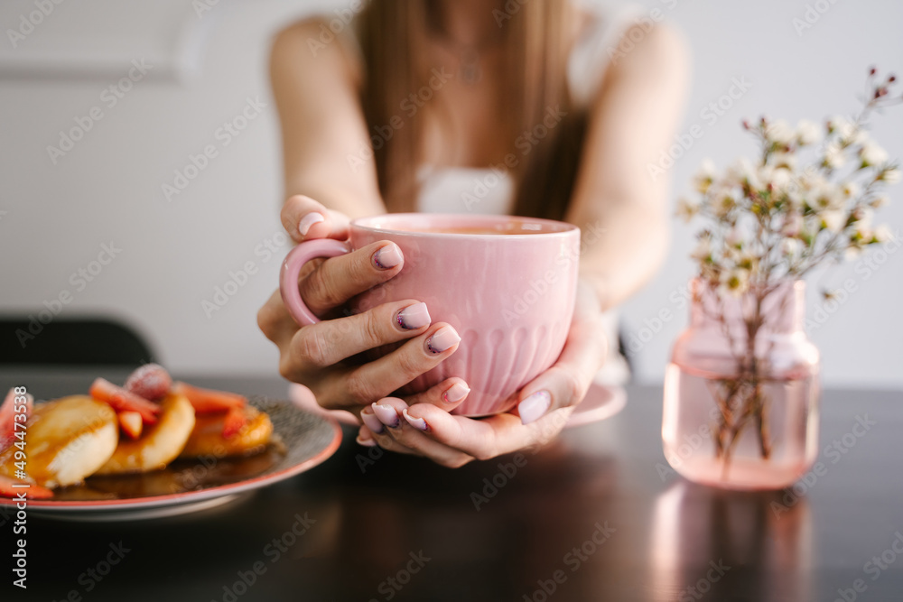 Woman's hand holds a pink mug with coffee, breakfast in a coffee shop Woman's hand holds a pink mug with coffee, breakfast in a coffee shop