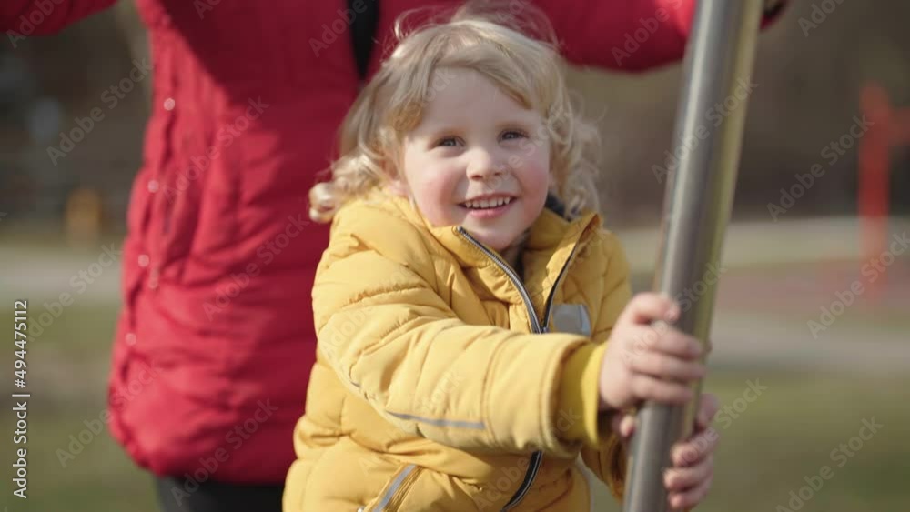 Blonde kid riding on outdoor gym equipment having fun with parents 4K Blonde kid riding on outdoor gym equipment having fun with parents 4K