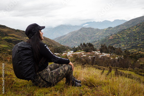 Hermosa foto de una feliz viajera hispana con una mochila sentada en la cima de montañas verdes © Yoel Garay