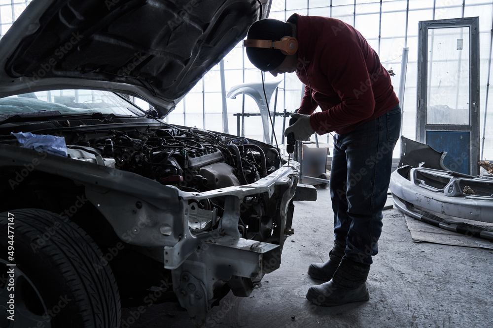 Car service worker repairs restores car