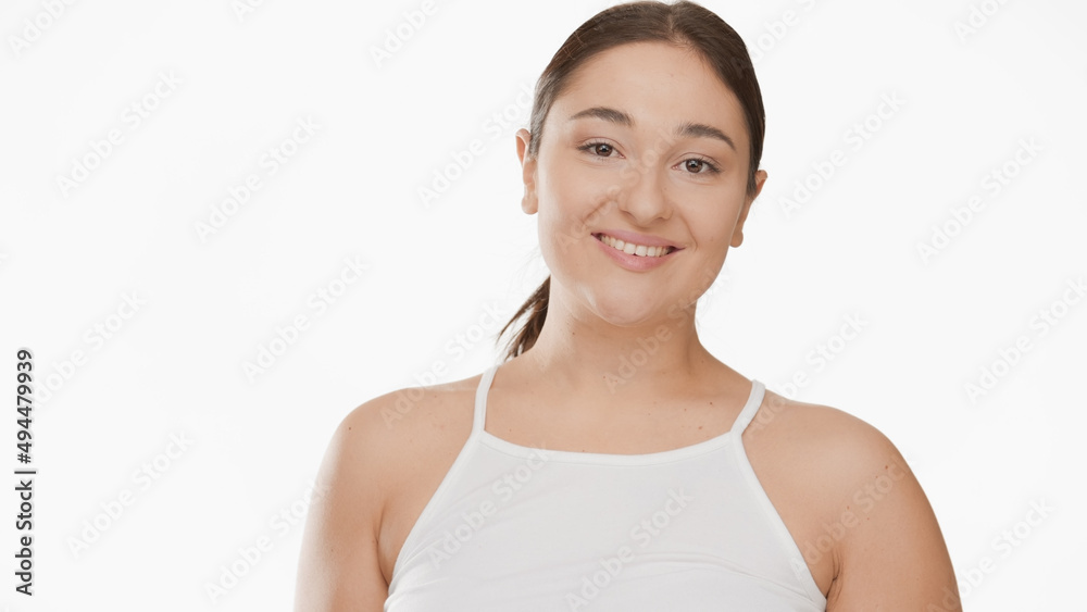 Pretty Caucasian young plus size woman with long dark hair in ponytail in white top smiling wide for the camera on white background | Smooth armpit concept Pretty Caucasian young plus size woman with long dark hair in ponytail in white top smiling wide for the camera on white background | Smooth armpit concept