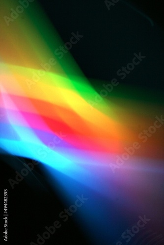 Luces en arcoiris a travès de un prisma con movimiento y desenfoque de luz incidente, refracta un bello diseño abstracto multicolor con fondo negro 