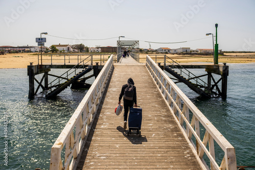 A man with bags on pier on Culatra Island, Algarve, Portugal