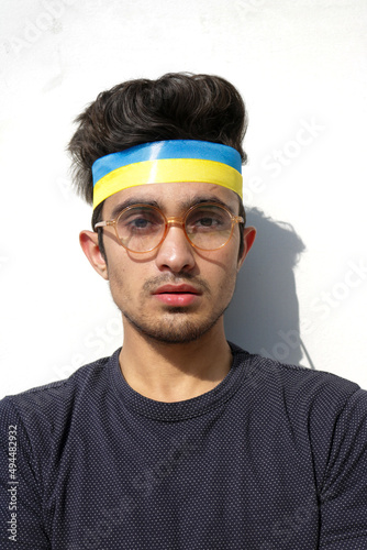 Vertical shot of a Young Guy wearing Ukrainian flag color ribbon on head in support of Ukraine. Solidarity with Ukraine.