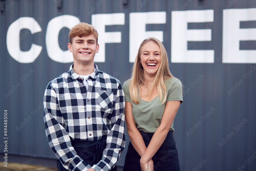 Portrait Of Male And Female Interns At Freight Haulage Business Standing By Shipping Container 