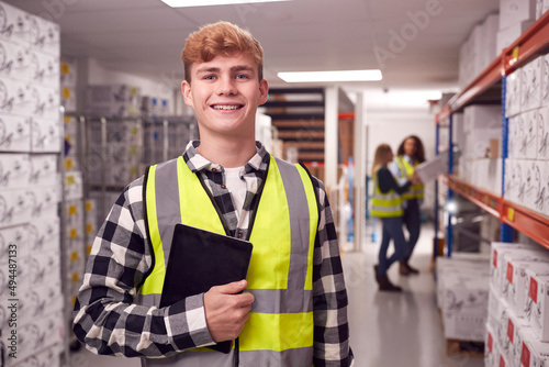 Tableau sur toile Portrait Of Male Worker Inside Busy Warehouse Checking Stock On Shelves Using Di