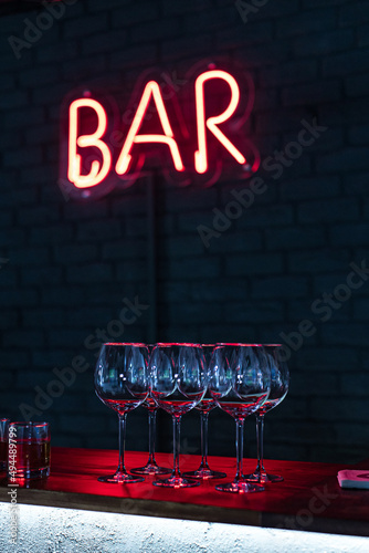 Glasses on bar neon sign background