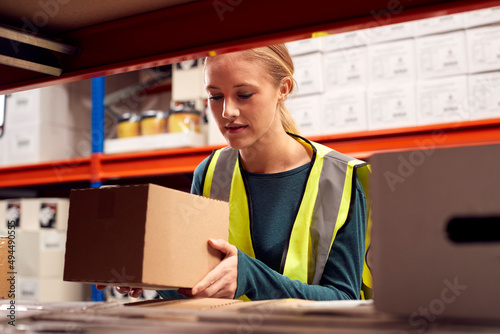 Obraz na plátně Female Worker Picking Box From Shelf Inside Warehouse