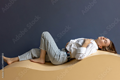 Portrait of a young woman lying on a geometric sand-colored couch.Abstract